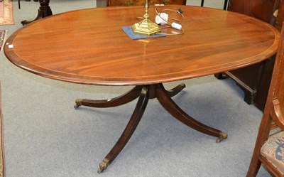 Lot 1220 - A 19th century mahogany dining table of Regency style, the oval crossbanded top on a gun barrel...