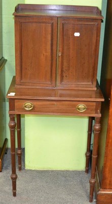 Lot 1303 - A mahogany cabinet on stand, the panelled doors opening to reveal an arrangement of drawers and...