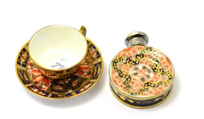 Lot 431 - A miniature Royal Crown Derby tea cup and saucer and a miniature scent bottle with silver cover