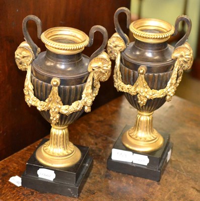 Lot 553 - A pair of ormolu mounted bronze twin handle urns each decorated with rams heads and floral swags on