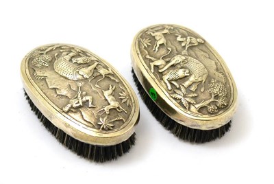 Lot 568 - A pair of Burmese silver backed gentleman's brushes decorated in repousse with hunting scenes