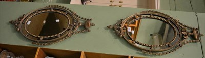 Lot 1427 - Pair of Period style oval sectional mirrors surmounted by urns and swags