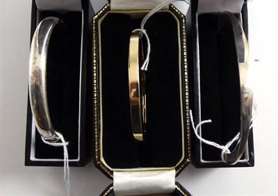 Lot 107 - A 9ct stiff hinge bangle, together with two silver stiff hinge bangles, cased (3)