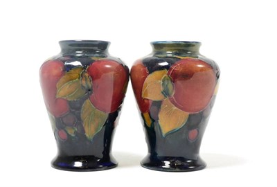 Lot 295 - Two William Moorcroft Pomegranate pattern baluster vases, on blue grounds, impressed factory...