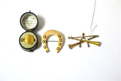 Lot 396 - A 9ct gold horseshoe brooch, a hunting brooch and an American dollar coin soldered as a ring (3)