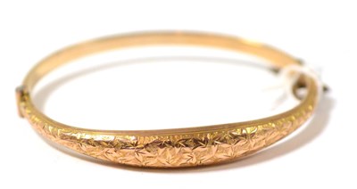 Lot 431 - A 9ct gold bangle, with foliate engraved front