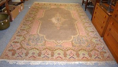 Lot 1174 - A Kirman design carpet, the pale camel field centred by a medallion framed by floral borders,...