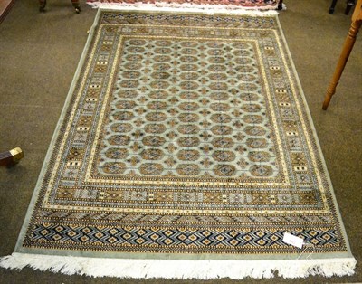 Lot 1323 - An artificial silk rug of Bakhara design, the mint green field with columns of quartered guls...