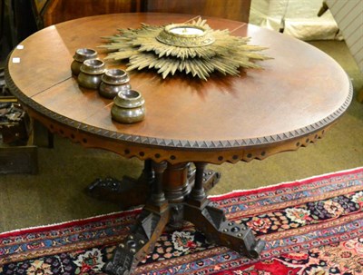 Lot 1336 - A 19th century oak tilt top circular breakfast table in the Gothic taste, the carved top raised...