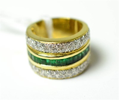 Lot 275 - ~An emerald and diamond ring, a row of baguette cut emeralds in a yellow channel setting within two