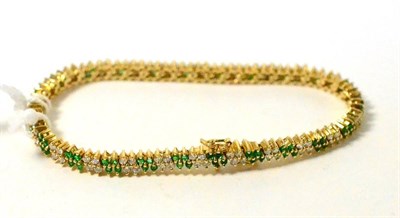 Lot 428 - ~An emerald and diamond bracelet, two rows of alternating pairs of round brilliant cut diamonds and