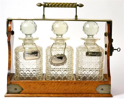 Lot 433 - An Edwardian three decanter tantalus, the plated mounts signed Betjemanns Patent, with two...