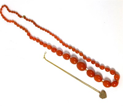 Lot 610 - A 9ct gold heart locket together with a string of amber coloured beads