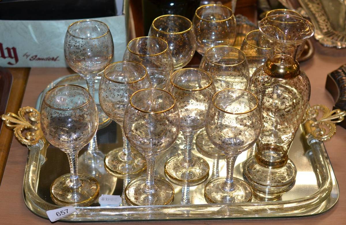 Lot 657 - A set of twelve glasses and decanter, with a gilt floral decoration, on a mirrored tray with...