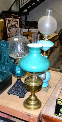 Lot 1088 - A large brass oil lamp with blue glass tapering base, a cast iron oil lamp and a brass oil lamp