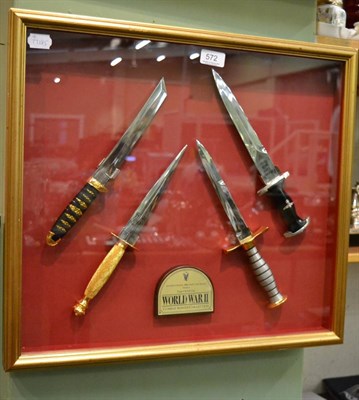 Lot 572 - A modern glazed display of four reproduction commando knives with a plaque inscribed...