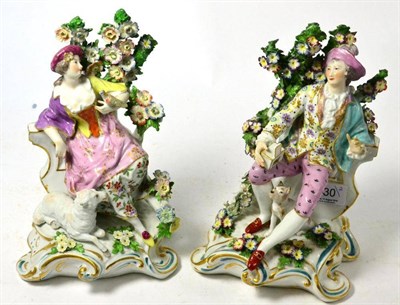 Lot 230 - A pair of Continental porcelain encrusted figurines modeled as a lady holding a bird and a...