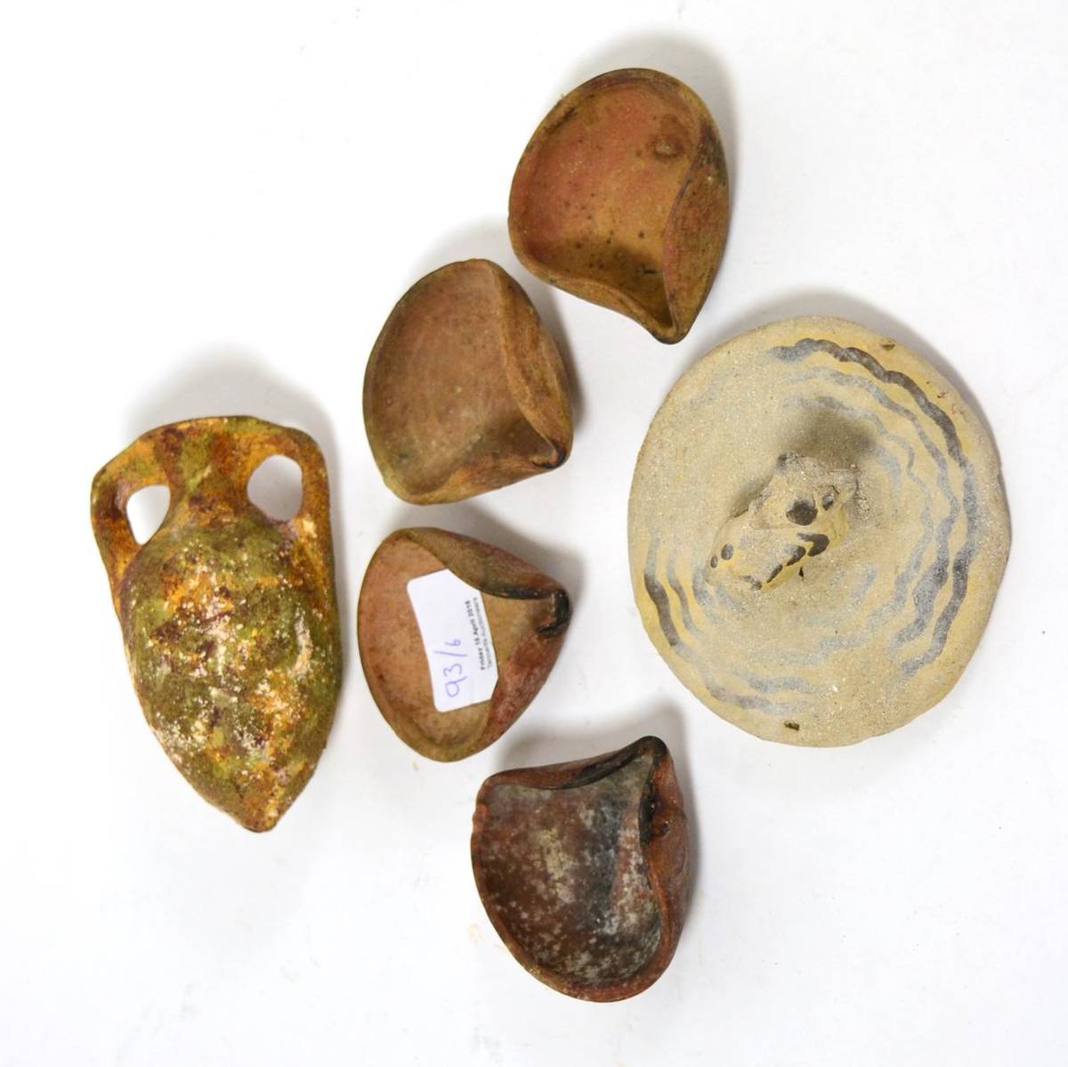 Lot 93 - Four Canaanite or Holy Land terracotta oil lamps, biblical period, of ear shape with pinched spout