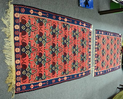 Lot 1316 - Pair of West Persian Kilims, each with a coral pink field of stylised plants enclosed by indigo...