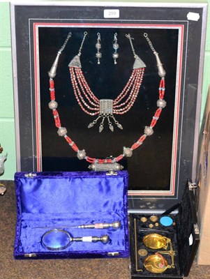 Lot 299 - A framed set of Yemeni jewellery, a cased set of gold scales together with a cased magnifying glass