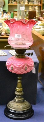 Lot 335 - A Victorian cranberry glass oil lamp with shade and chimney