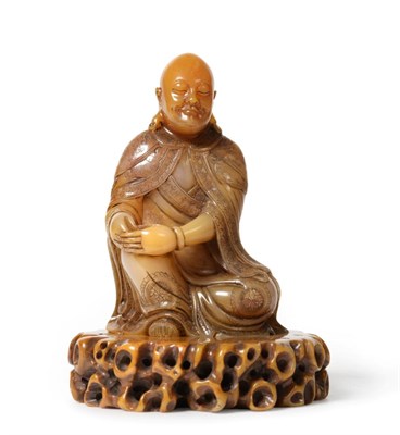 Lot 81 - A Chinese Soapstone Figure of a Lohan, sitting wearing flowing robes, on a carved and pierced...