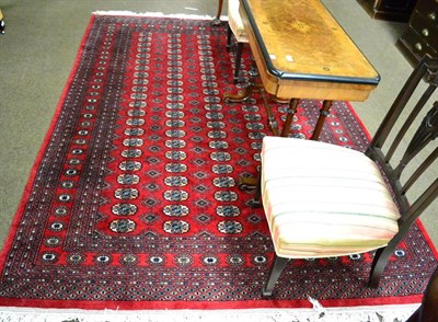 Lot 1338 - A Lahore Bokhara rug, Punjab, the claret field with five columns of guarded guls enclosed by...