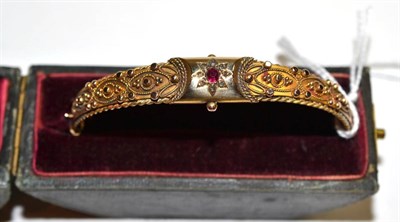 Lot 25 - A 9ct gold red stone and diamond bangle, cased