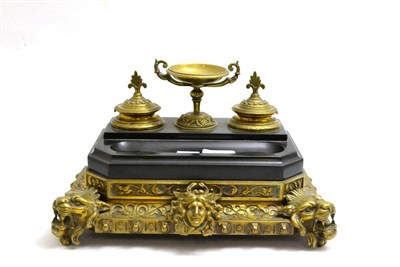 Lot 11 - A Victorian gilt metal black slate desk standish, surmounted by an urn and raised on front lion...