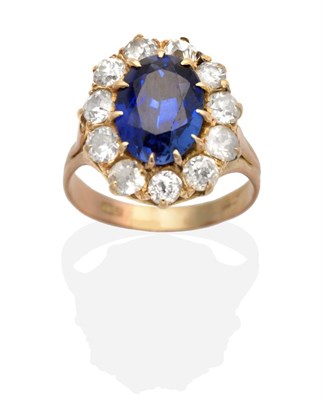 Lot 189 - A Sapphire and Diamond Cluster Ring, an oval cut sapphire in a claw setting, within a border of old