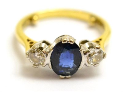 Lot 87 - An 18ct gold sapphire and diamond three stone ring, the oval cut sapphire flanked by a round...