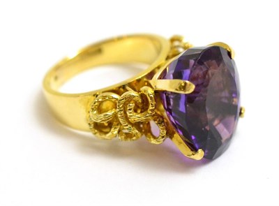 Lot 105 - An amethyst ring, an oval mixed cut amethyst in a yellow claw setting, to textured scrolling...
