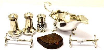 Lot 245 - A silver sauce boat, three silver pepperettes and a pair of silver knife rests together with a...