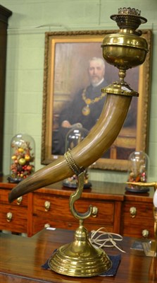 Lot 427 - A Victorian oil lamp, the brass font and burner mounted on a cows horn, supported on a domed...