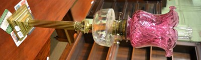 Lot 429 - A Victorian oil lamp with brass Corinthian column, clear glass font and a cranberry shade