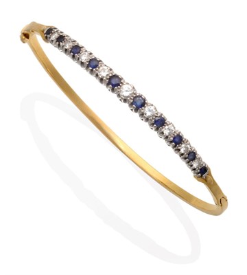Lot 251 - An 18 Carat Gold Sapphire and Diamond Bangle, of graduating round brilliant cut diamonds and...