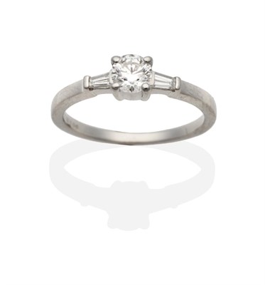 Lot 267 - A Platinum Diamond Ring, a round brilliant cut diamond between two tapered baguette cut...