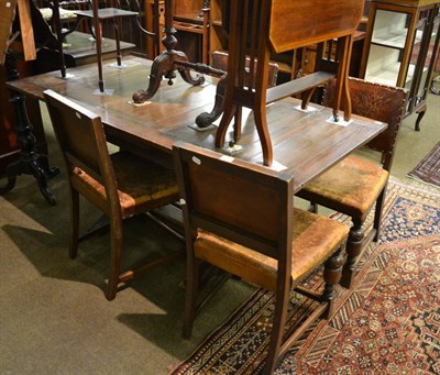 Lot 1216 - An oak draw leaf table and a set of four dining chairs with leather and studded upholstery