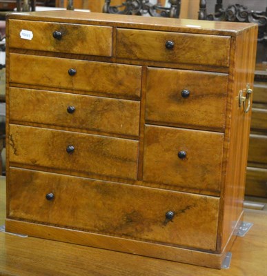 Lot 1290 - A small walnut cabinet fitted with an arrangement of drawers and twin brass carrying handles