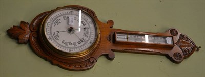 Lot 1321 - A light oak carved wheel barometer