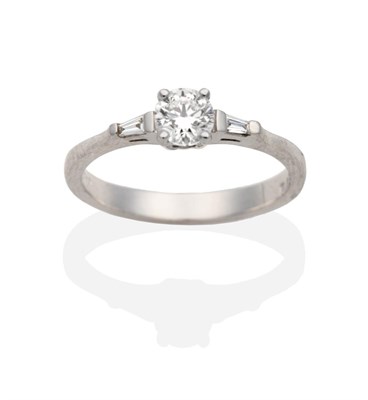 Lot 331 - A Platinum Diamond Ring, a round brilliant cut diamond between tapered baguette cut diamonds,...