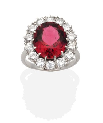 Lot 332 - A Pink Tourmaline and Diamond Cluster Ring, an oval cut pink tourmaline in a claw setting, within a