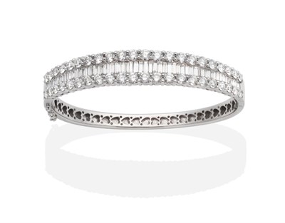 Lot 359 - An 18 Carat White Gold Diamond Bangle, graduated channel set baguette cut diamonds between bands of