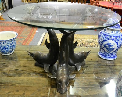 Lot 1192 - A circular glass top coffee table, the metal base in the form of dolphin, diameter 76cm