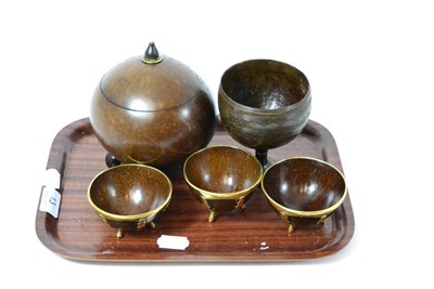 Lot 13 - Three small brass mounted coconut cups on tripod feet, coconut cup with carved floral...