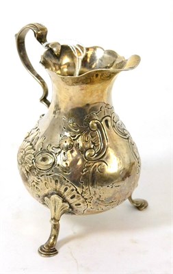 Lot 411 - A silver cream jug on tripod feet