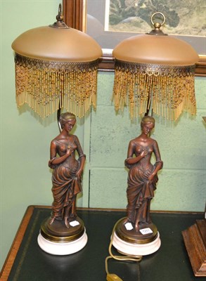 Lot 1251 - A pair of figural bronzed lamps with bead shades