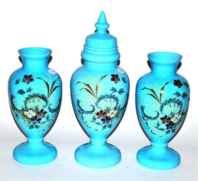 Lot 31 - A garniture of three Victorian enamelled blue glass vases, one with cover