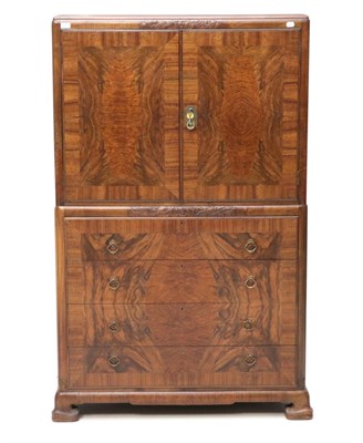 Lot 644 - An Art Deco Figured Walnut Tallboy, the top section with two doors enclosing a shelf, the base with