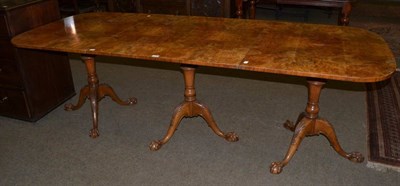 Lot 1353 - A burr walnut triple pedestal dining table raised on ball and claw feet